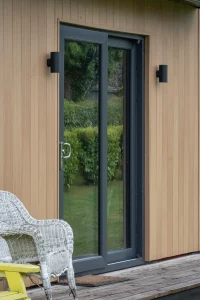 Black frame sliding door on light brown wooden panels on modular home in Connacht
